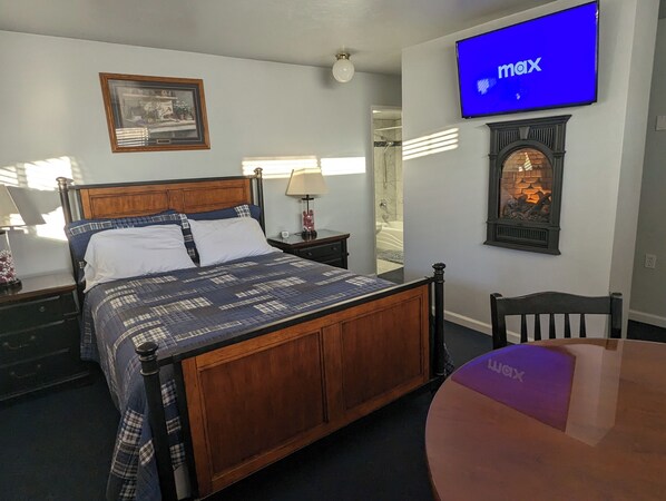 A hotel room with a bed, a TV, a fireplace, and a mirror. - Majestic Rockies Motel (Sandy)