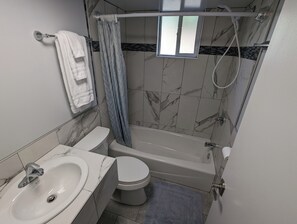 Deluxe kamer | Badkamer | Een bad/douchecombinatie, handdoeken, zeep, shampoo