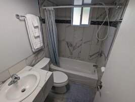 Bañera con ducha, toallas, jabón, shampoo