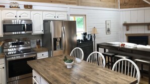 Una cucina moderna con mobili bianchi, elettrodomestici in acciaio inossidabile e un tavolo da pranzo in legno.
