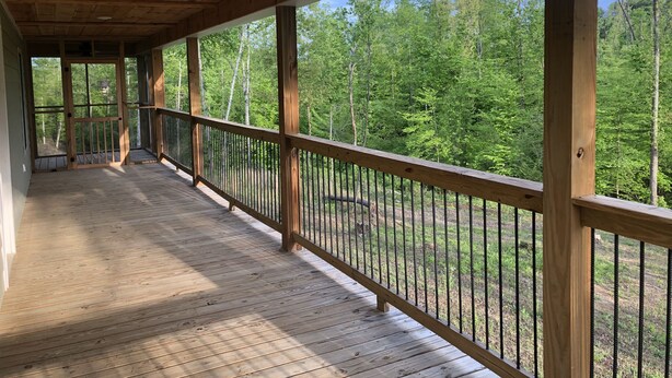 Un terrazzo in legno con ringhiera che si affaccia su una zona boschiva.
