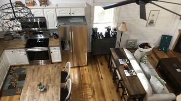 A modern kitchen with stainless steel appliances, a dining area with a wooden table and chairs, and a ceiling fan.