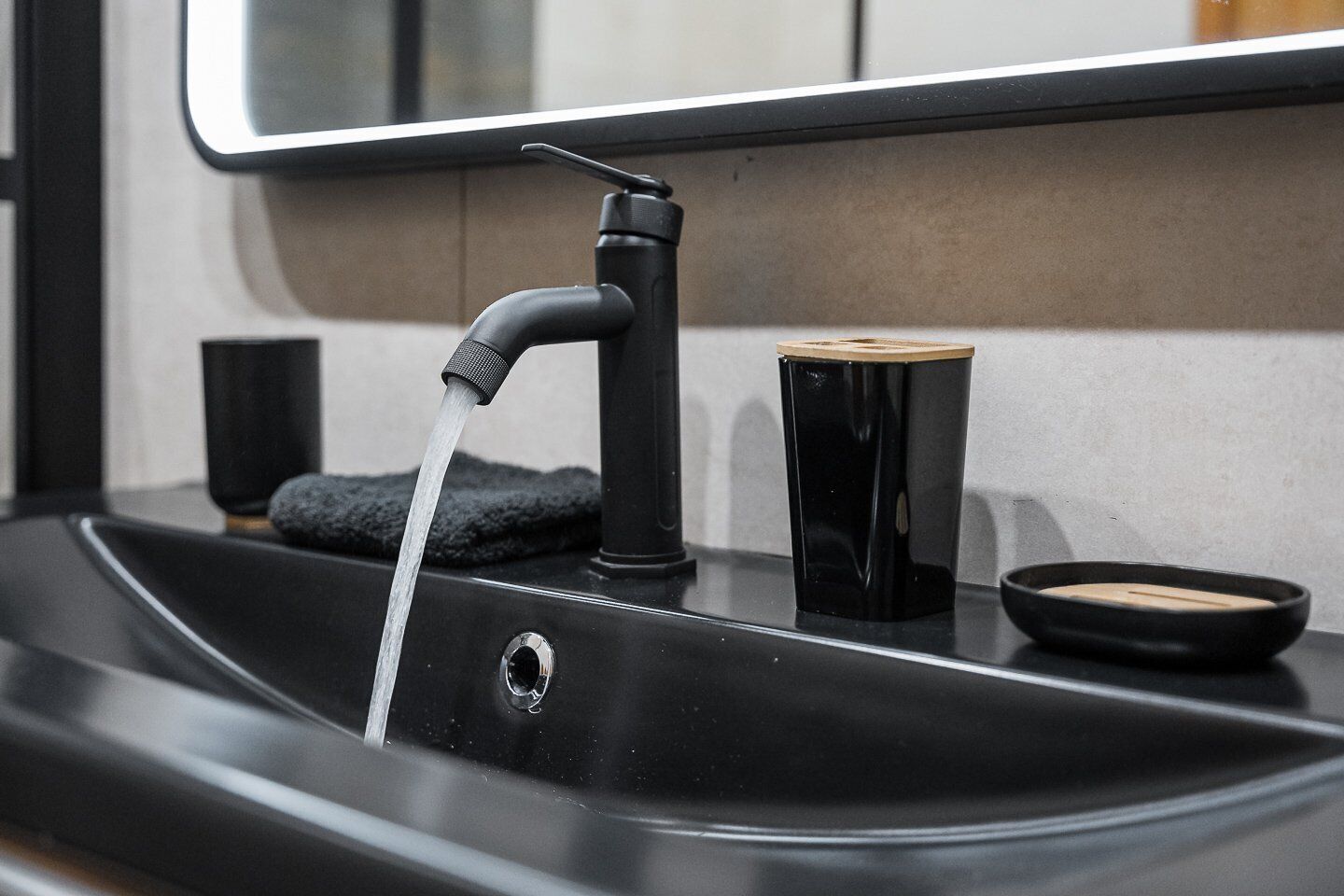 Un lavabo de salle de bain moderne, doté d’un robinet noir, d’un porte-savon et d’une serviette.