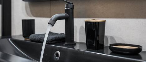 Un lavabo de salle de bain moderne, doté d’un robinet noir, d’un porte-savon et d’une serviette.