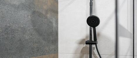 Une douche moderne dotée d’un pommeau de douche à main et d’un panneau de commande fixé au mur.