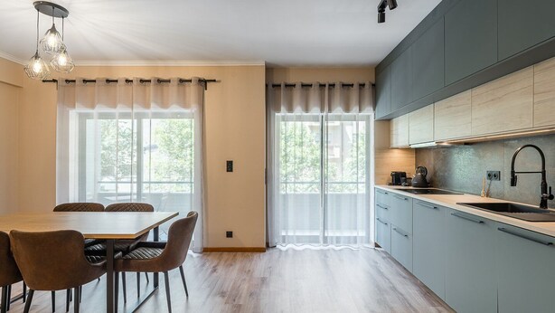 A modern kitchen with a dining area, featuring light wood flooring, a dining table with chairs, and a large window with sheer curtains. - GuestReady - A breath of fresh air in Nogueiró (Nogueiró)