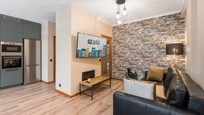 A modern living room with a black leather sofa, a wooden coffee table, and a brick-patterned wall. - GuestReady - A breath of fresh air in Nogueiró (Nogueiró)