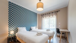A hotel room with two beds, a desk, a chair, a lamp, and a window with curtains. - GuestReady - A breath of fresh air in Nogueiró (Nogueiró)