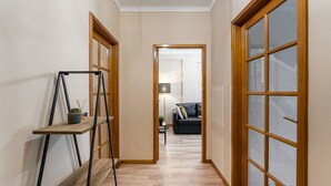 A hallway with a wooden floor, a ladder, and a door leading to a living room with a sofa and a lamp. - GuestReady - A breath of fresh air in Nogueiró (Nogueiró)