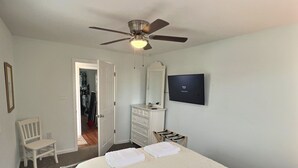 A bedroom with a bed, a ceiling fan, a dresser, a TV, and a chair. - Reed's Beach - Stunning waterfront Sunsets - Bay Front Home Steps to beach (Middle Township)
