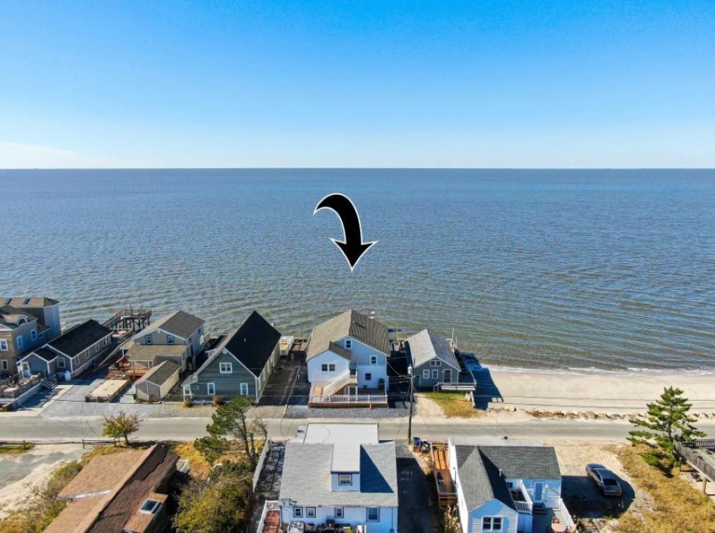 A coastal residential area with houses and a road leading to the beach.