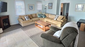 A living room with a beige sectional sofa, a wooden coffee table, a grey armchair, and a ceiling fan. - Reed's Beach - Stunning waterfront Sunsets - Bay Front Home Steps to beach (Middle Township)