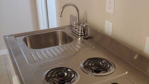 Una cocina con un lavamanos doble, dos fogones a gas y una encimera de acero inoxidable.