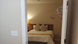 Un dormitorio con cama, mesita de noche y perchero.