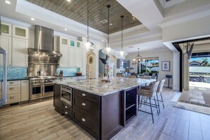 Una cocina moderna con una isla grande, electrodomésticos de acero inoxidable e iluminación colgante.