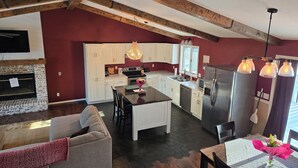Una cocina moderna con armarios blancos, una isla central y un refrigerador de acero inoxidable.
