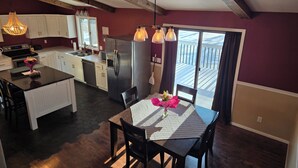 Una cocina moderna con armarios blancos, un refrigerador de acero inoxidable y un comedor con mesa y sillas.