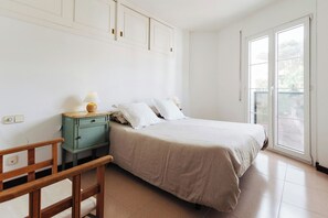 A bedroom with a bed, a nightstand, a chair, and a window with a view.