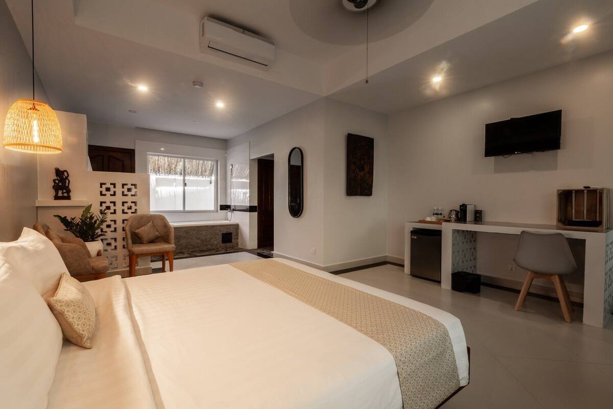 Una habitación de hotel moderna con una cama grande, un escritorio, una silla y un televisor.