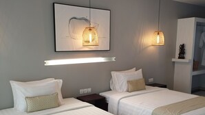 A modern hotel room with two beds, a large artwork above the beds, and pendant lighting. - La bastide de Caro (Siem Reap)