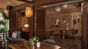 A wooden interior with a dining area, seating, and a bar. - La bastide de Caro (Siem Reap)