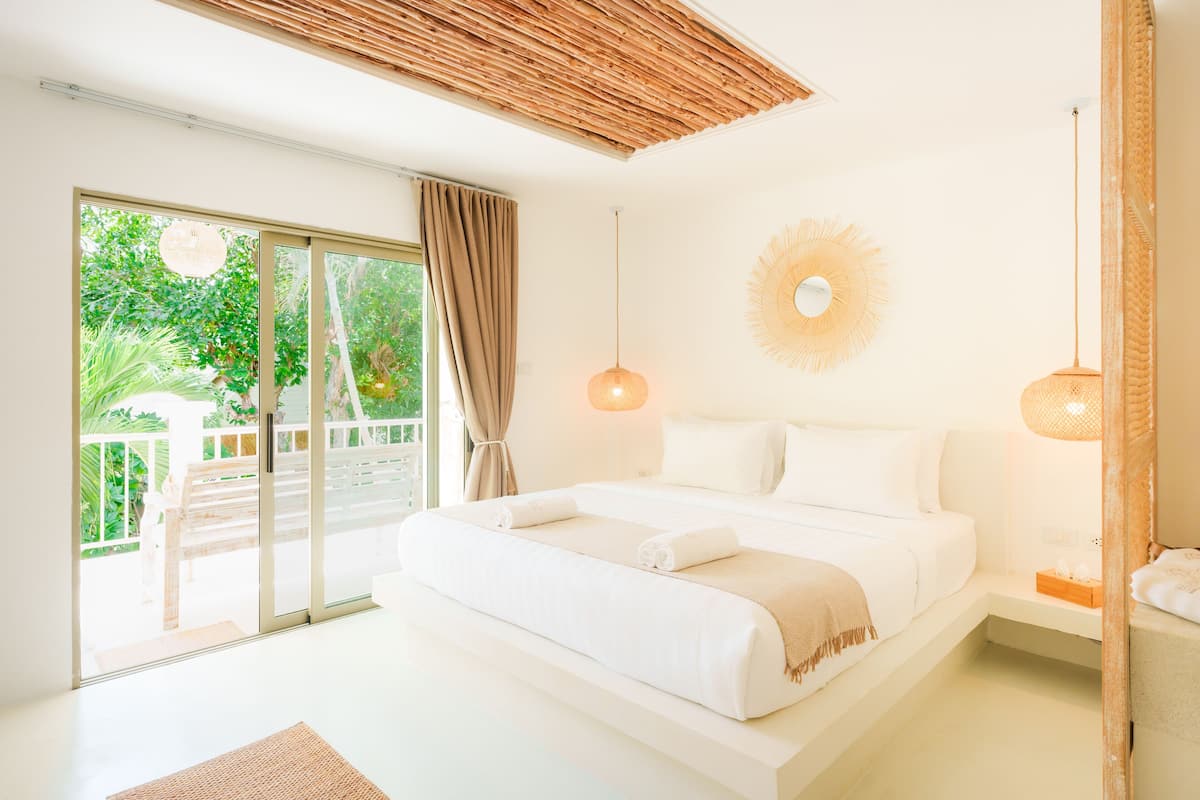 Un dormitorio moderno con una cama grande, puertas de cristal correderas a un balcón y un techo con diseño de madera natural.