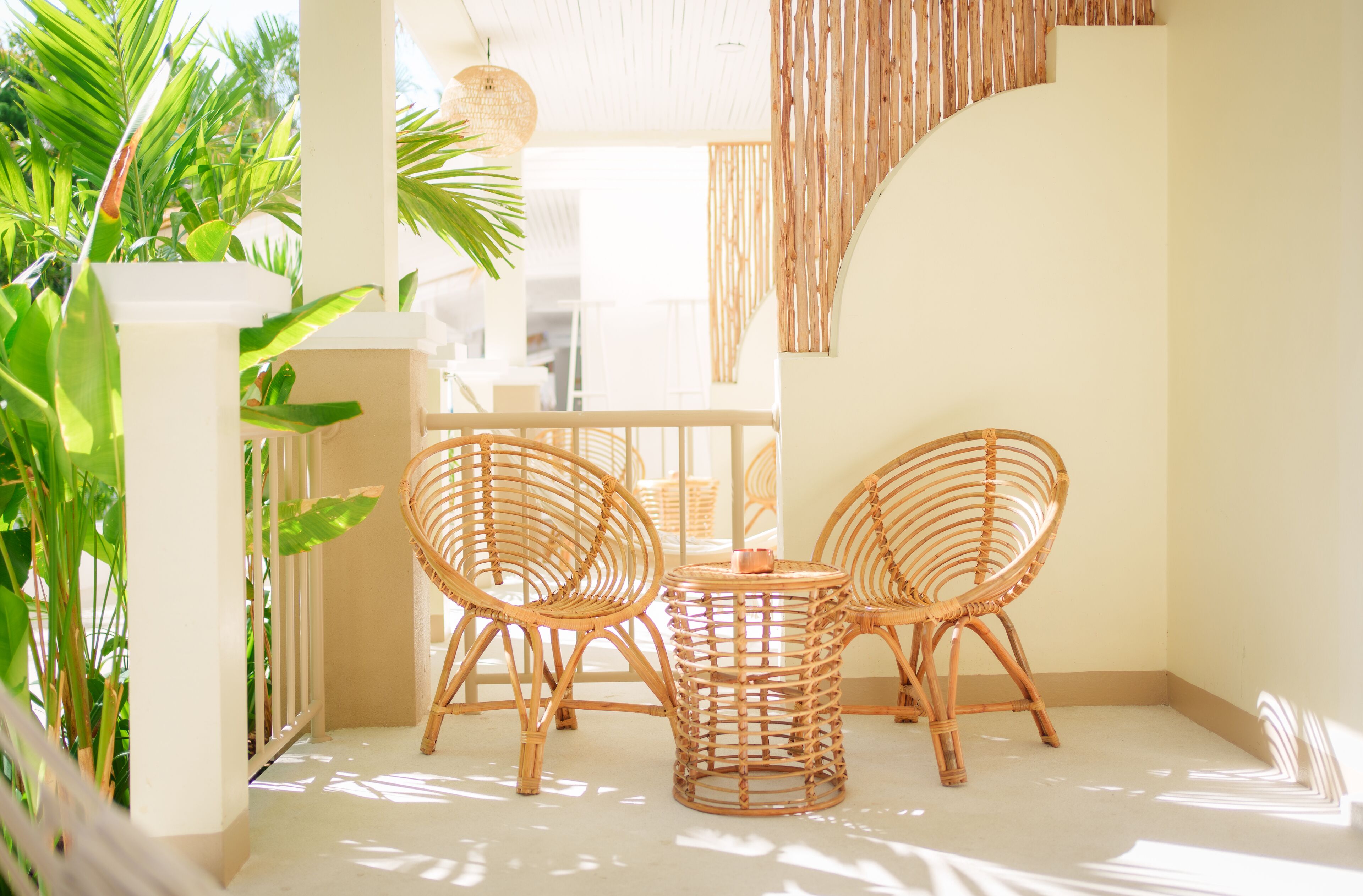 A bright, sunlit room with a white ceiling, a small round table, and two wicker chairs.