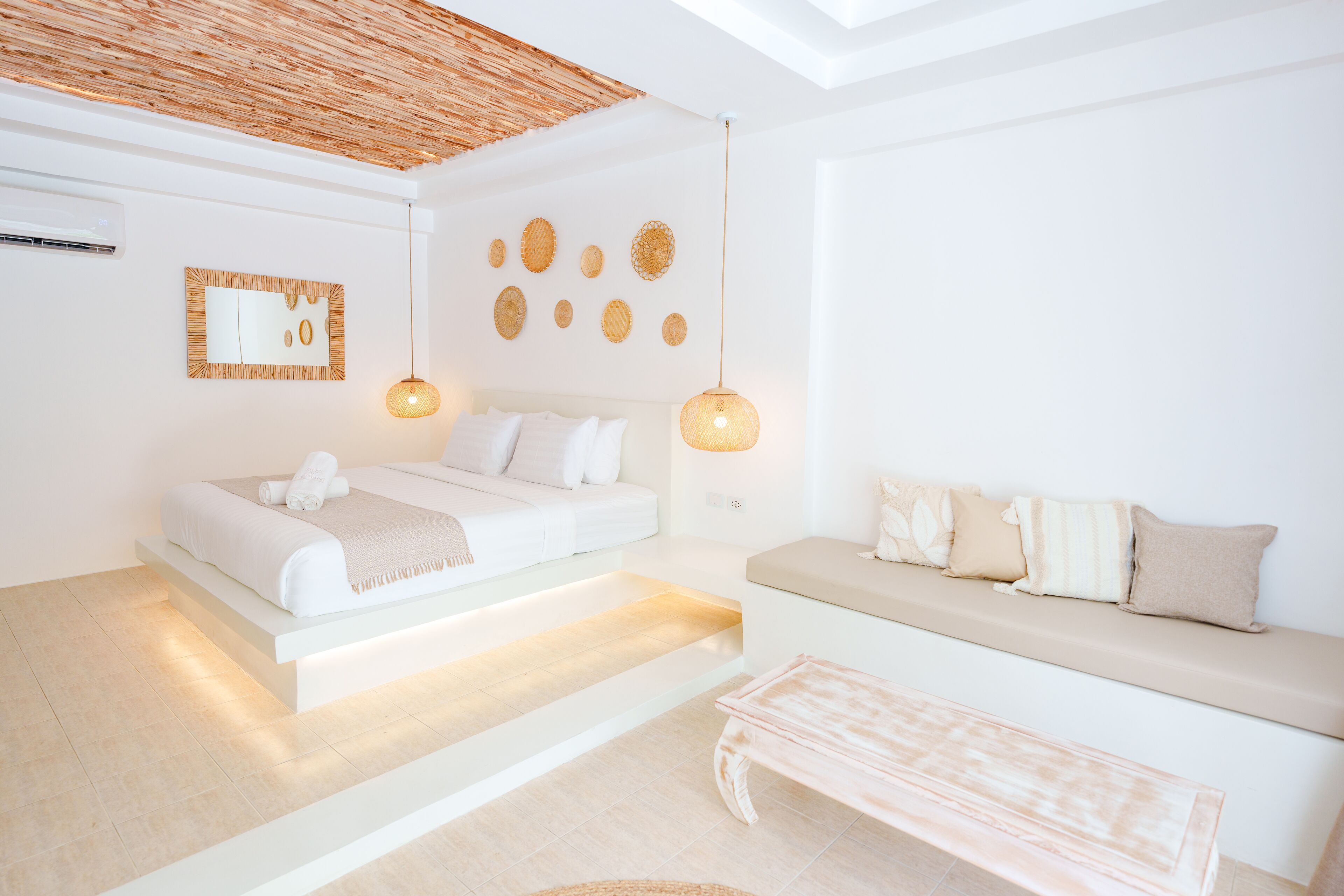 A modern bedroom with a bed, a sofa, and a hanging light fixture.