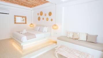 A modern bedroom with a bed, a sofa, and a hanging light fixture.