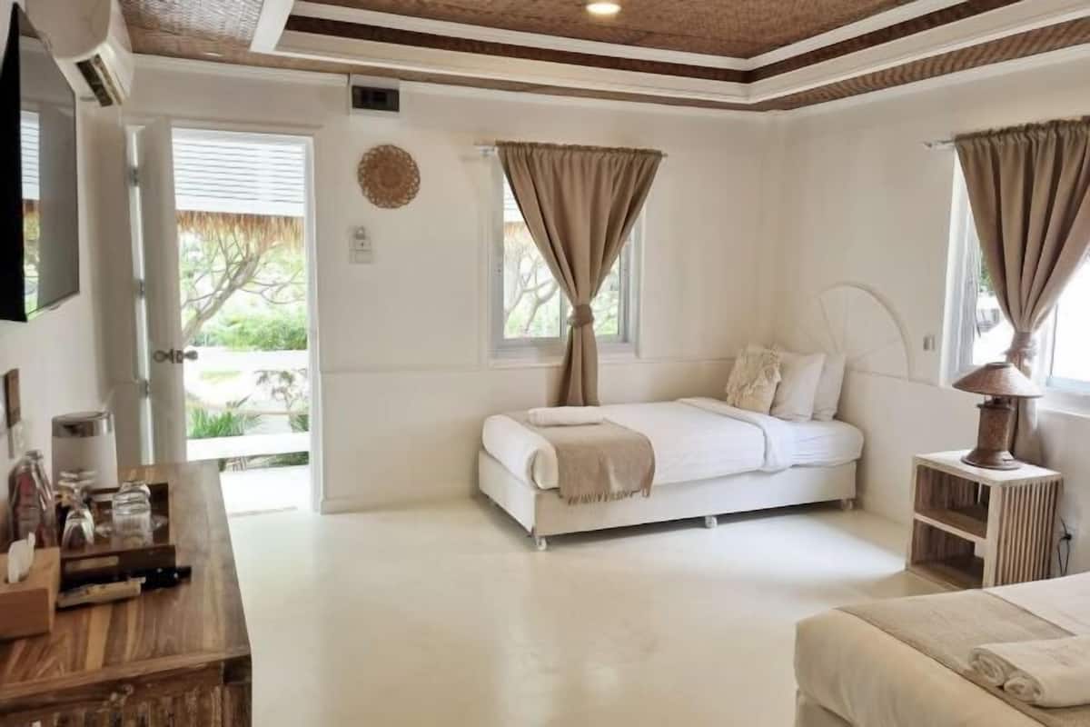 Un dormitorio con cama, mesita de noche y ventana con cortinas.