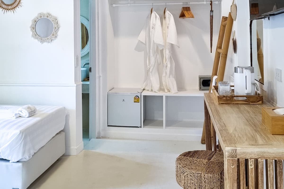 Un dormitorio con cama, una mesita de noche, una silla de madera, un armario y un espejo en la pared.