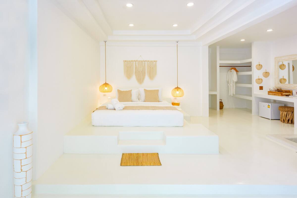 Un dormitorio moderno con una cama grande, lámparas de noche y una paleta de colores neutros.