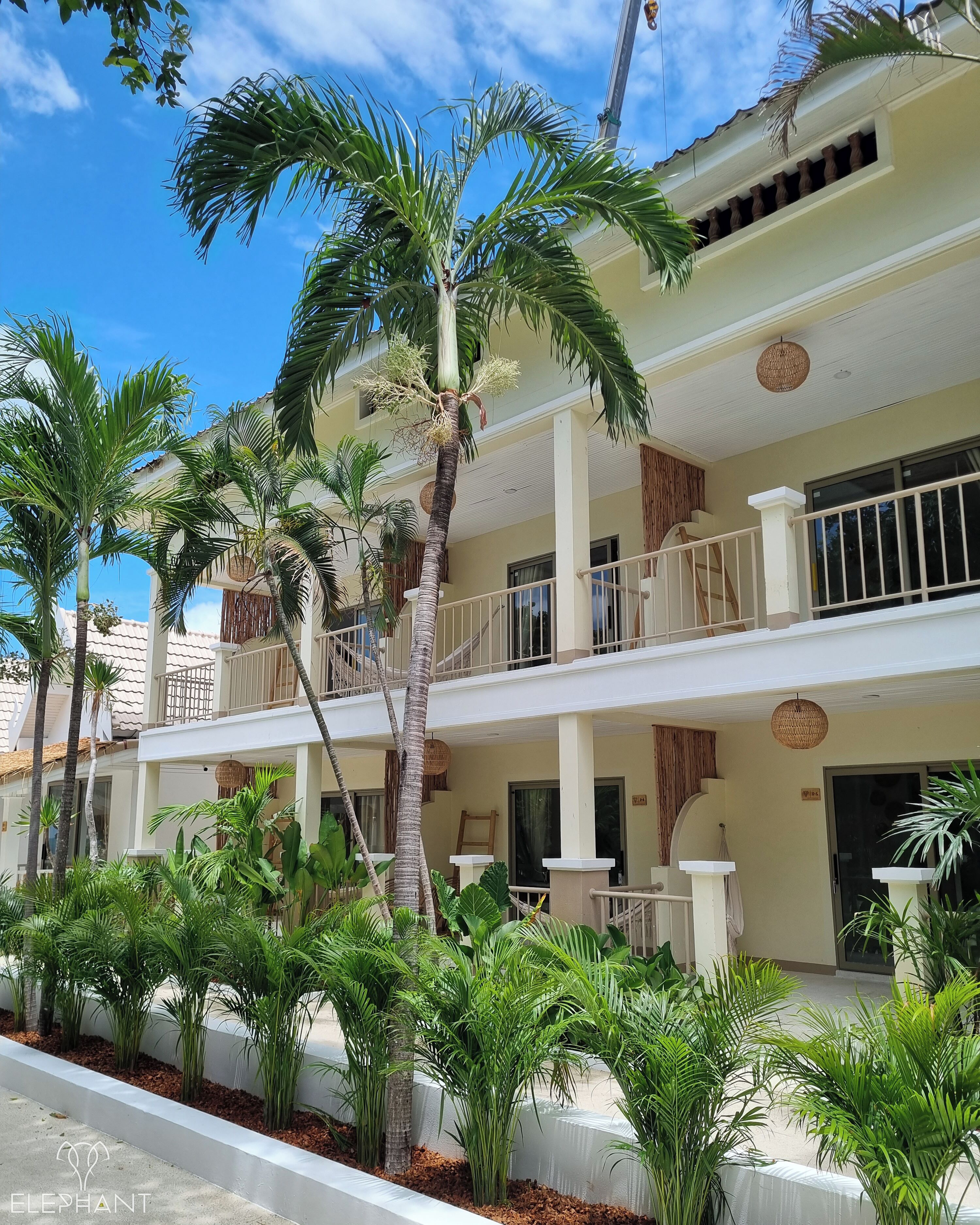 A hotel with a two-story structure, outdoor seating, and palm trees.