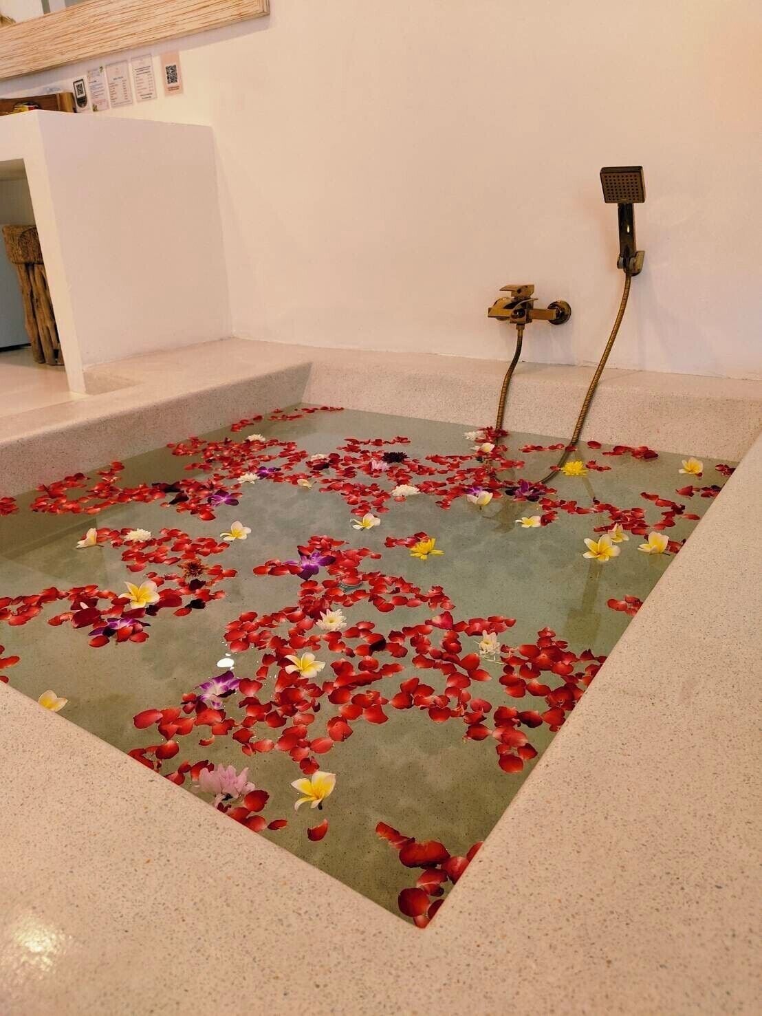 Une baignoire remplie de pétales de rose et un pommeau de douche.