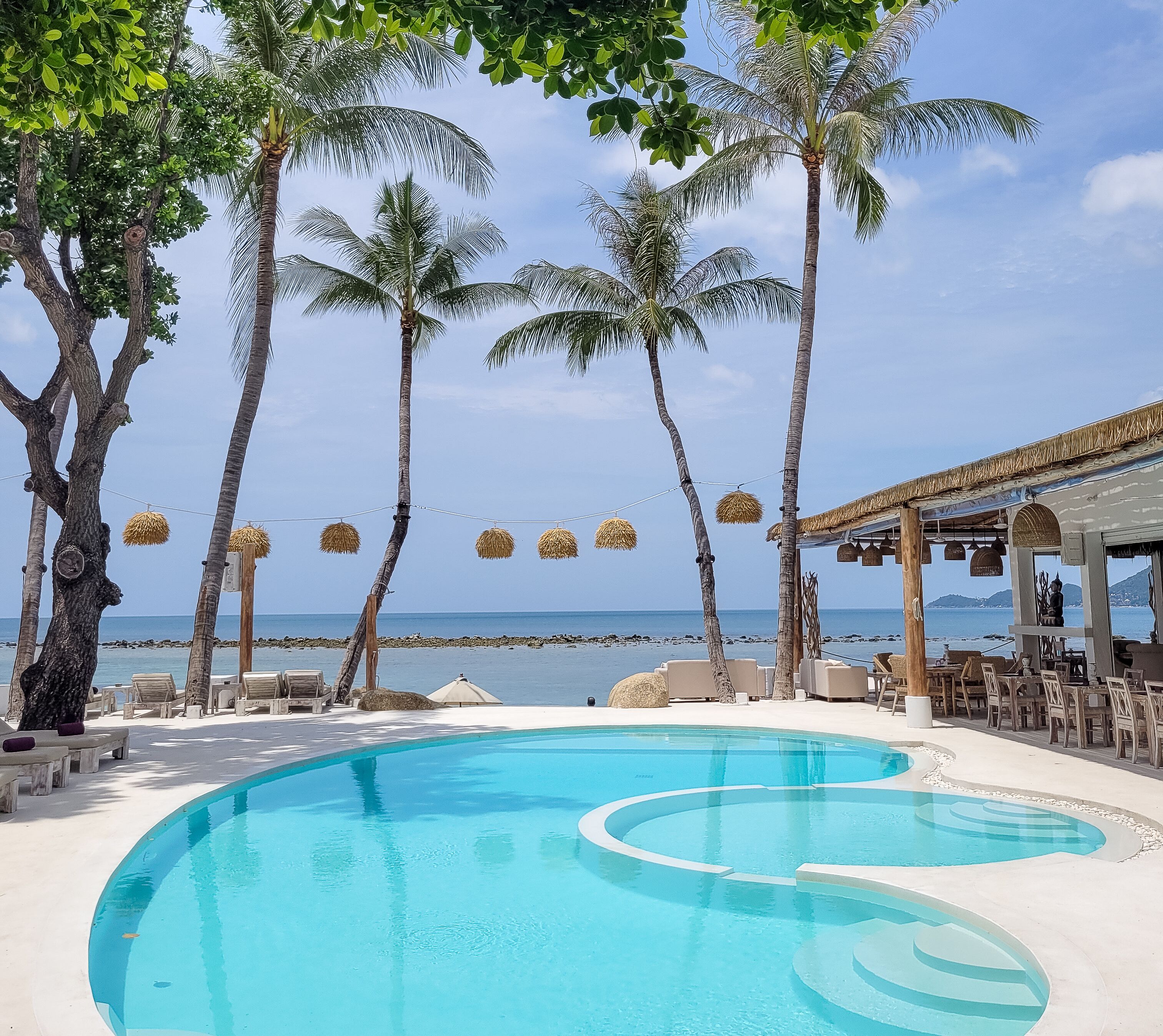Una piscina al aire libre, sombrillas, sillones reclinables de piscina