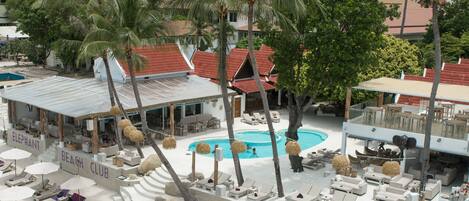 A resort with a swimming pool, lounge chairs, and palm trees.