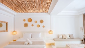 A modern bedroom with a large bed, a sofa, and a small table. - Elephant Beach Club & Resort Samui (Koh Samui)