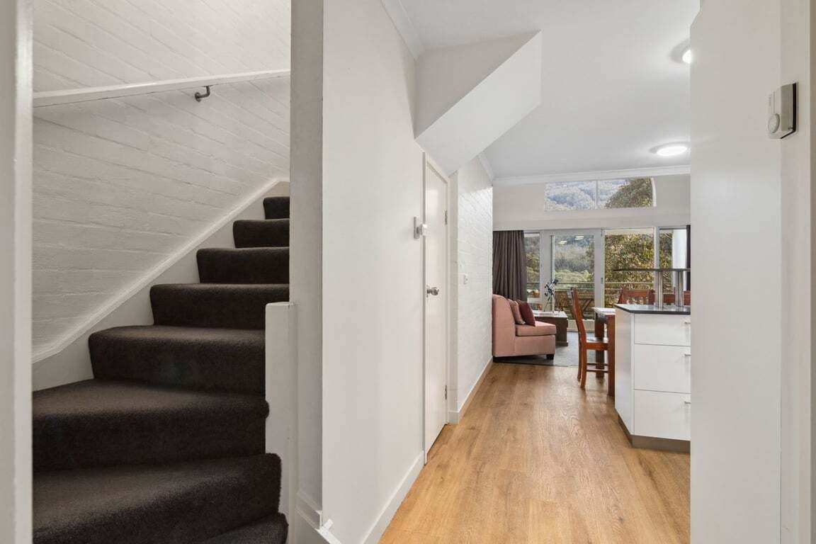 A staircase leading to a living area with a sofa and a dining table.