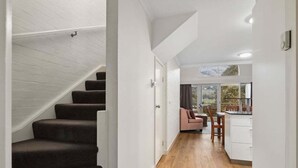 A staircase leading to a living area with a sofa and a dining table. - Inala 2 is an exceptional top floor, one bedroom and loft apartment. (Thredbo)
