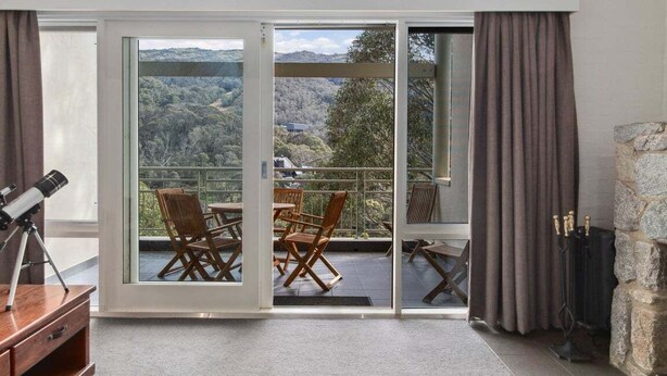 A room with a large sliding glass door leading to a balcony with outdoor furniture. - Inala 2 is an exceptional top floor, one bedroom and loft apartment. (Thredbo)