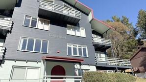 A multi-story building with a red door, white-framed windows, and balconies.