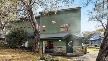 A two-story building with a stone foundation and a green exterior.