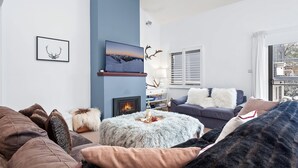 Een moderne woonkamer met een open haard, een wandgemonteerde televisie en een gezellige zithoek.