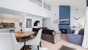 Een moderne woonkamer met een open haard, een eethoek en een keuken.