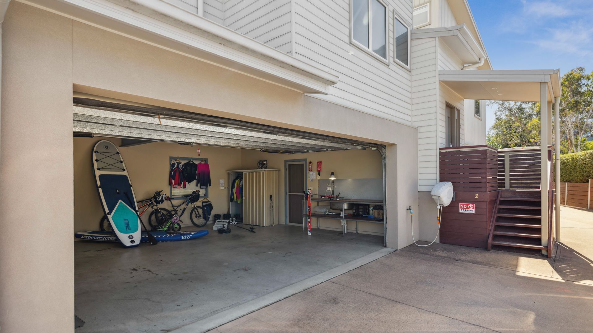 A garage with a bicycle, surfboard, and sports equipment.