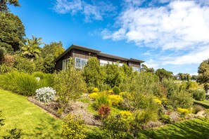 A modern house surrounded by lush greenery and a clear blue sky.