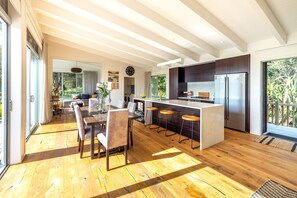 A modern kitchen with a central island, wooden flooring, and large windows.
