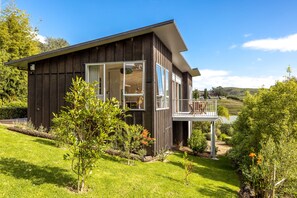 Ein modernes Haus mit Balkon, umgeben von einem gepflegten Garten und einer schönen Hanglage.