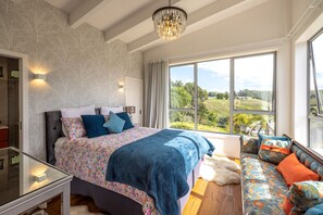 Una camera da letto con un letto grande, un divano, un lampadario e vista sull'esterno.