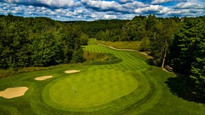A golf course with sand bunkers, a putting green, and a flagstick. - Summer Adventure Retreat - Golf Views, King Beds, Fully Loaded Kitchen! (Mancelona)